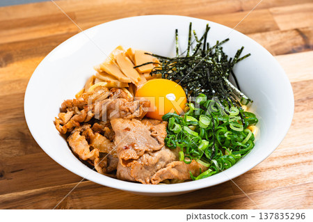 油拌麵配豬肉和生蛋；自製什錦麵，盛於木桌上。 137835296