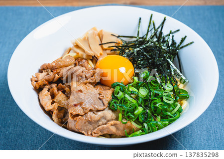Oil noodles topped with pork and a raw egg; homemade mixed noodles on the table. Oil noodles topped with pork and a raw egg; homemade mixed noodles on the table. 137835298