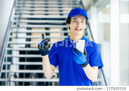 倉庫裡的一名男性工人手持智慧型手機。 137835510