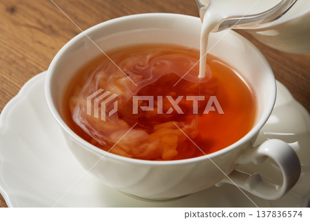 Adding milk to tea 137836574