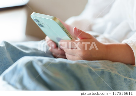 A girl's hands as she uses her smartphone A girl's hands as she uses her smartphone 137836611
