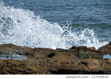 A fleeting moment as white waves crash violently against the rock face and break apart. A fleeting moment as white waves crash violently against the rock face and break apart. 137836634