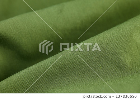 High-angle macro of olive green technical fabric showing diagonal weave and soft material folds 137836656