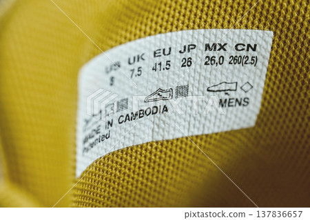 White tag inside a yellow shoe showing international size charts and Made in Cambodia text White tag inside a yellow shoe showing international size charts and Made in Cambodia text 137836657