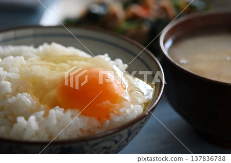 A scene from the dinner table: rice with raw egg on top. 137836788