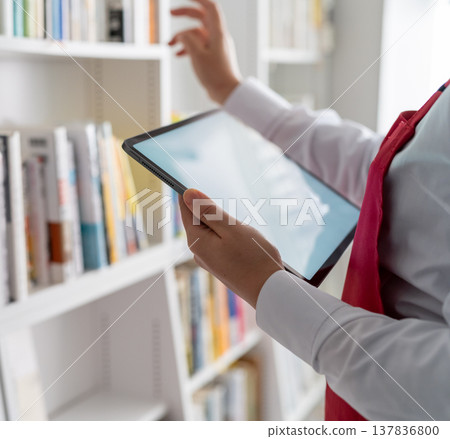 A store employee checks the shelves using a tablet. A store employee checks the shelves using a tablet. 137836800
