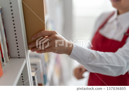 雙手從書架上取下一本書 137836805