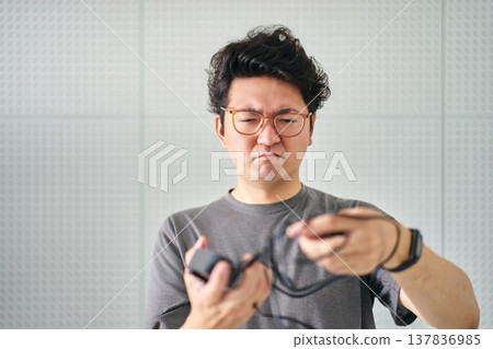 A man with a frustrated and troubled expression tries to untangle tangled wiring and power cords. 137836985