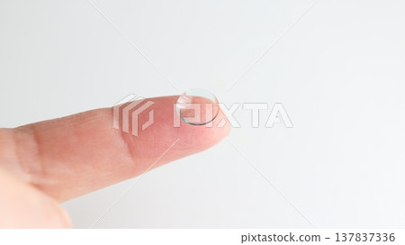 A hard contact lens placed on the index finger. A hard contact lens placed on the index finger. 137837336