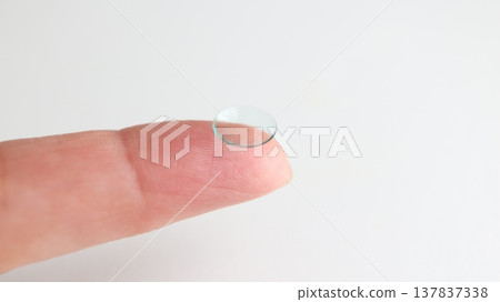 A hard contact lens placed on the index finger. A hard contact lens placed on the index finger. 137837338