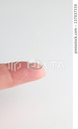 A hard contact lens placed on the index finger. A hard contact lens placed on the index finger. 137837339