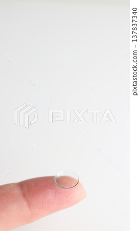 將一副硬式隱形眼鏡戴在食指上。 將一副硬式隱形眼鏡戴在食指上。 137837340