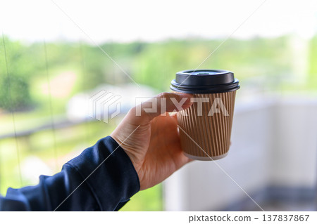 Looking outside with a cup of coffee in hand Looking outside with a cup of coffee in hand 137837867
