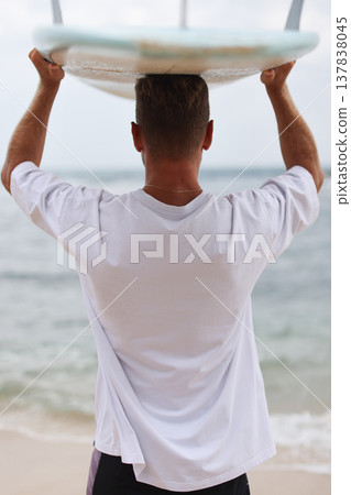 Surfer In Sunlit Coastal Environment. Beachside Man Preparing To Surf Against Sunlight Background Surfer In Sunlit Coastal Environment. Beachside Man Preparing To Surf Against Sunlight Background 137838045