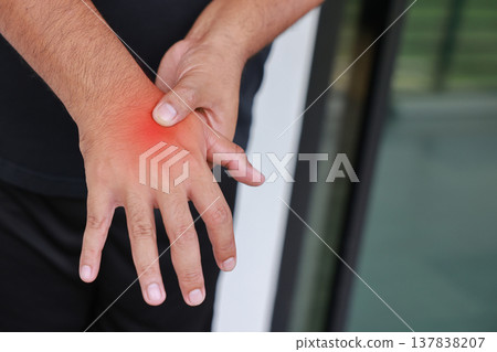 Close up of a man massaging his painful hand and wrist with a red glowing spot indicating joint inflammation, arthritis, tendonitis or carpal tunnel syndrome. Medical healthcare and injury concept. Close up of a man massaging his painful hand and wrist with a red glowing spot indicating joint inflammation, arthritis, tendonitis or carpal tunnel syndrome. Medical healthcare and injury concept. 137838207