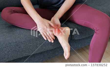 Woman massaging painful ankle and foot with red highlight. Ankle sprain, tendonitis, foot pain, gout and inflammation concept for health care, physical therapy and orthopedic medical treatment. Woman massaging painful ankle and foot with red highlight. Ankle sprain, tendonitis, foot pain, gout and inflammation concept for health care, physical therapy and orthopedic medical treatment. 137838252