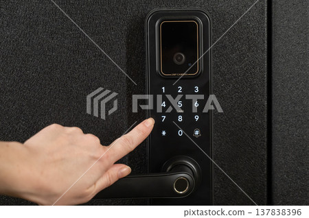 A woman opens a modern smart door lock with a digital keypad using a code. 137838396