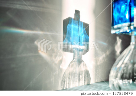 Perfume bottle shadow creating blue light refraction on wall Perfume bottle shadow creating blue light refraction on wall 137838479