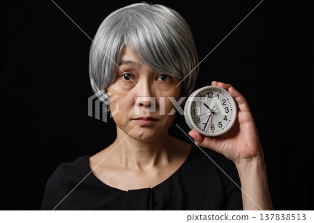 A senior woman with white hair and a round watch, expressionless face. 137838513