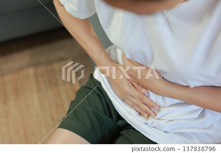 Woman holding her stomach with red highlight. Abdominal pain, liver disease, kidney pain, appendicitis and stomach ache concept for health care and medical treatment. Woman holding her stomach with red highlight. Abdominal pain, liver disease, kidney pain, appendicitis and stomach ache concept for health care and medical treatment. 137838796