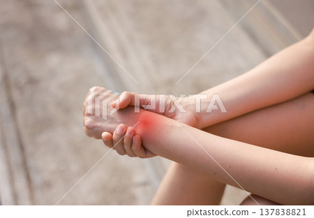 Close up of woman holding her painful wrist with red highlight. Carpal tunnel syndrome, sprain, tendonitis and joint inflammation concept for health care and medical treatment. Close up of woman holding her painful wrist with red highlight. Carpal tunnel syndrome, sprain, tendonitis and joint inflammation concept for health care and medical treatment. 137838821