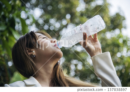 Young Woman Drinking Water bottle outdoor park traveler. Asian female drinking water bottle healthy person happy smile. Happiness Beautiful asian chinese women holding mineral water bottle lifestyle 137838897