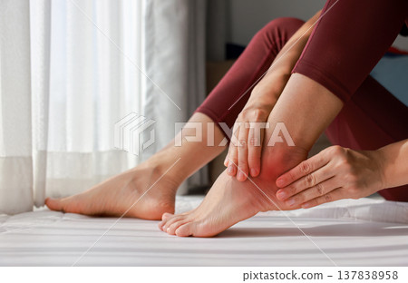 Woman massaging her painful knee and ankle with red highlight. Knee osteoarthritis, ankle sprain, joint inflammation and injury concept for health care, physical therapy and medical treatment. 137838958