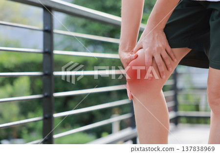 Close up of woman standing and holding her painful knee with red highlight. Sport injury, ligament tear, runner's knee and joint inflammation concept for health care and physical therapy. Close up of woman standing and holding her painful knee with red highlight. Sport injury, ligament tear, runner's knee and joint inflammation concept for health care and physical therapy. 137838969