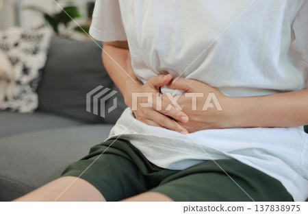 Woman holding her stomach with red highlight. Abdominal pain, liver disease, kidney pain, appendicitis and stomach ache concept for health care and medical treatment. Woman holding her stomach with red highlight. Abdominal pain, liver disease, kidney pain, appendicitis and stomach ache concept for health care and medical treatment. 137838975