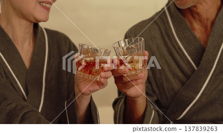 Senior couple drinking whiskey in the bedroom, no faces Senior couple drinking whiskey in the bedroom, no faces 137839263