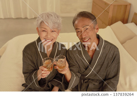 Senior couple drinking whiskey in the bedroom, portrait, looking at camera Senior couple drinking whiskey in the bedroom, portrait, looking at camera 137839264
