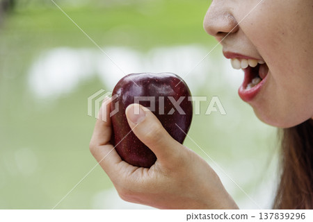 Young asian woman eating red Apple Healthy. Girl workout holding organic apple fruit healthy lifestyle. Wellness Asian women eat red apple smile face look at camera. Beauty health care lifestyle Young asian woman eating red Apple Healthy. Girl workout holding organic apple fruit healthy lifestyle. Wellness Asian women eat red apple smile face look at camera. Beauty health care lifestyle 137839296