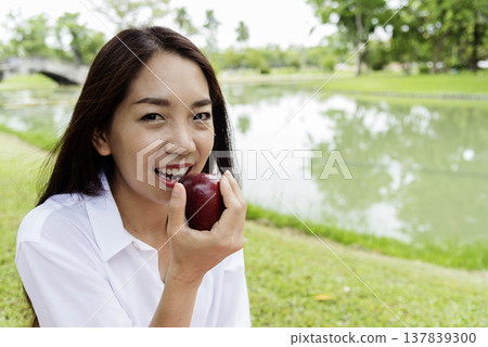 Young asian woman eating red Apple Healthy. Girl workout holding organic apple fruit healthy lifestyle. Wellness Asian women eat red apple smile face look at camera. Beauty health care lifestyle Young asian woman eating red Apple Healthy. Girl workout holding organic apple fruit healthy lifestyle. Wellness Asian women eat red apple smile face look at camera. Beauty health care lifestyle 137839300