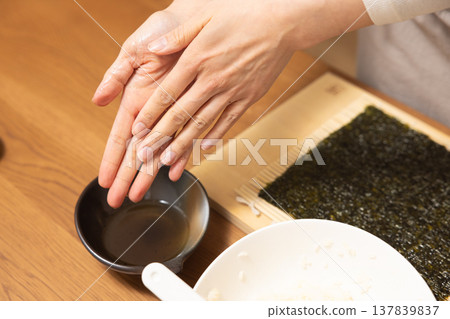特寫:一位女士的手正在製作江方捲(吉利方向壽司捲)。 特寫:一位女士的手正在製作江方捲(吉利方向壽司捲)。 137839837