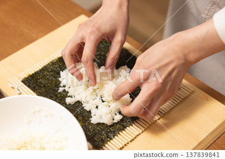 Close-up of a woman's hands making Ehomaki (lucky direction sushi roll). 137839841