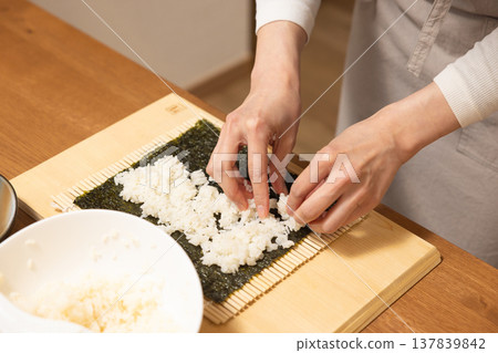 Close-up of a woman's hands making Ehomaki (lucky direction sushi roll). Close-up of a woman's hands making Ehomaki (lucky direction sushi roll). 137839842
