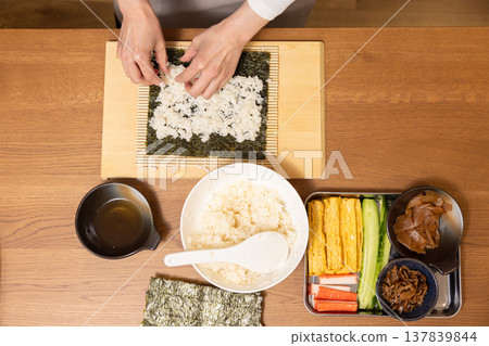 Close-up of a woman's hands making Ehomaki (lucky direction sushi roll). 137839844