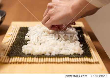 Close-up of a woman's hands making Ehomaki (lucky direction sushi roll). 137839846