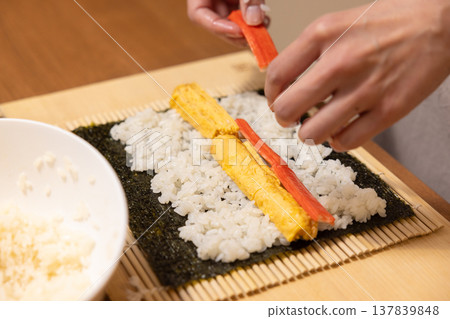 特寫：一位女士的手正在製作江方捲（吉利方向壽司捲）。 137839848