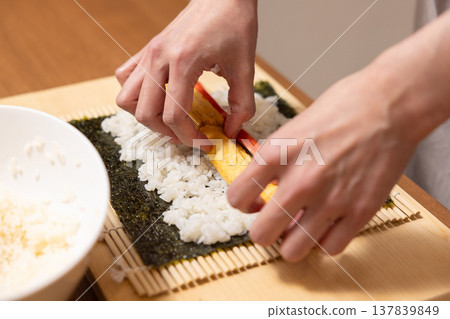 Close-up of a woman's hands making Ehomaki (lucky direction sushi roll). 137839849