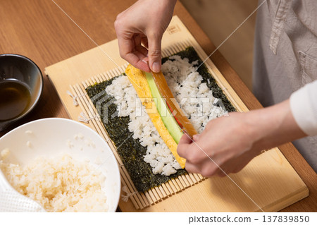 特寫:一位女士的手正在製作江方捲(吉利方向壽司捲)。 特寫:一位女士的手正在製作江方捲(吉利方向壽司捲)。 137839850