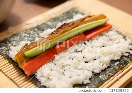 Close-up of a woman's hands making Ehomaki (lucky direction sushi roll). 137839852