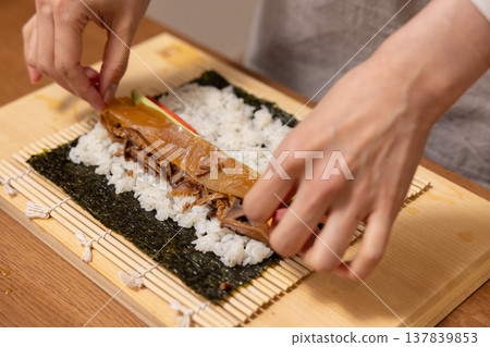 Close-up of a woman's hands making Ehomaki (lucky direction sushi roll). 137839853