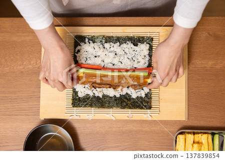 特寫：一位女士的手正在製作江方捲（吉利方向壽司捲）。 137839854