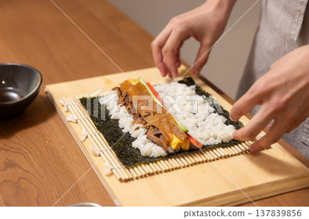 特寫:一位女士的手正在製作江方捲(吉利方向壽司捲)。 特寫:一位女士的手正在製作江方捲(吉利方向壽司捲)。 137839856