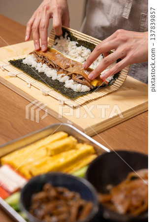 Close-up of a woman's hands making Ehomaki (lucky direction sushi roll). 137839857