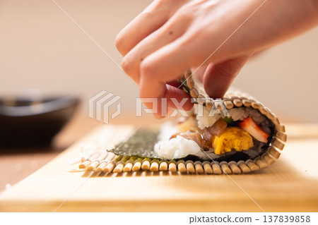 Close-up of a woman's hands making Ehomaki (lucky direction sushi roll). 137839858