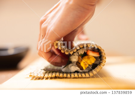 Close-up of a woman's hands making Ehomaki (lucky direction sushi roll). 137839859