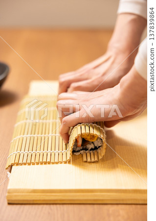 Close-up of a woman's hands making Ehomaki (lucky direction sushi roll). 137839864