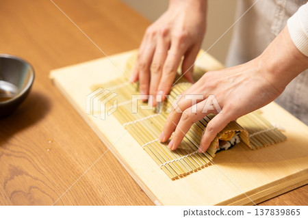Close-up of a woman's hands making Ehomaki (lucky direction sushi roll). 137839865
